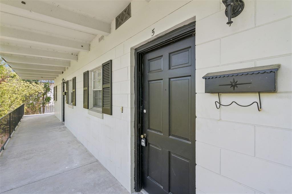 A black front door with a mailbox is located on a covered concrete walkway — 791 LAKE AVENUE UNIT 5, CLERMONT, FL