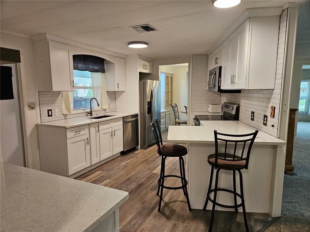 A covered porch features green siding, a white door, a chair, and a blue bin — 217 LAKE TARPON DRIVE UNIT 24, PALM HARBOR, FL
