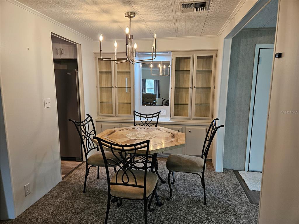 A covered carport features a parked SUV, a golf cart, and light-colored siding — 217 LAKE TARPON DRIVE UNIT 24, PALM HARBOR, FL