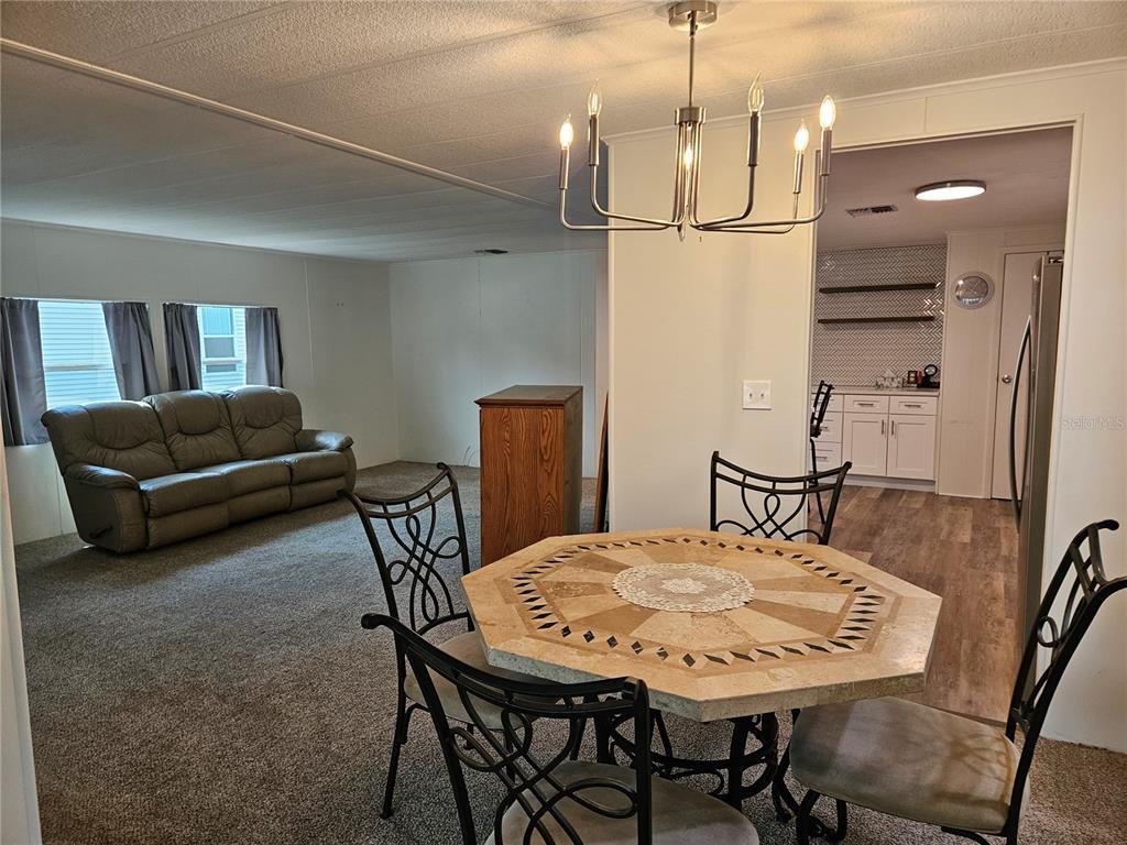 A kitchen with white cabinets, stainless steel appliances, a breakfast bar, and herringbone tile backsplash — 217 LAKE TARPON DRIVE UNIT 24, PALM HARBOR, FL