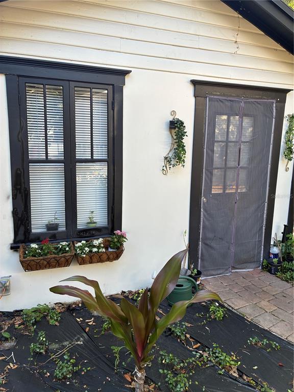 A white exterior wall features a black-framed window with flower boxes and a screened door — 407 N SHINE AVENUE, ORLANDO, FL