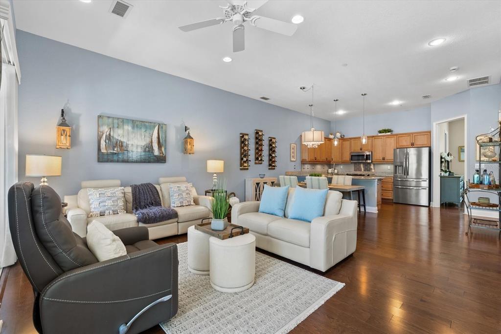 An open-concept living room and kitchen featuring light blue walls and hardwood flooring — 429 NOKOMIS AVENUE S, VENICE, FL