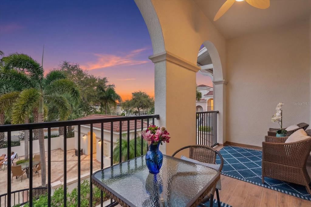 A covered balcony features a glass-top table, wicker chairs, a blue rug, and sunset views — 429 NOKOMIS AVENUE S, VENICE, FL