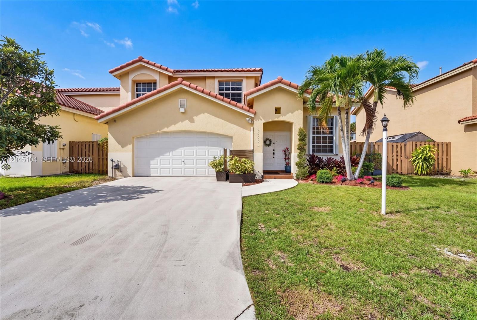 A two-story suburban house with a beige stucco exterior, tile roof, and a two-car garage — 15602 SW 109th Ter, Miami FL 33196, MIAMI, FL