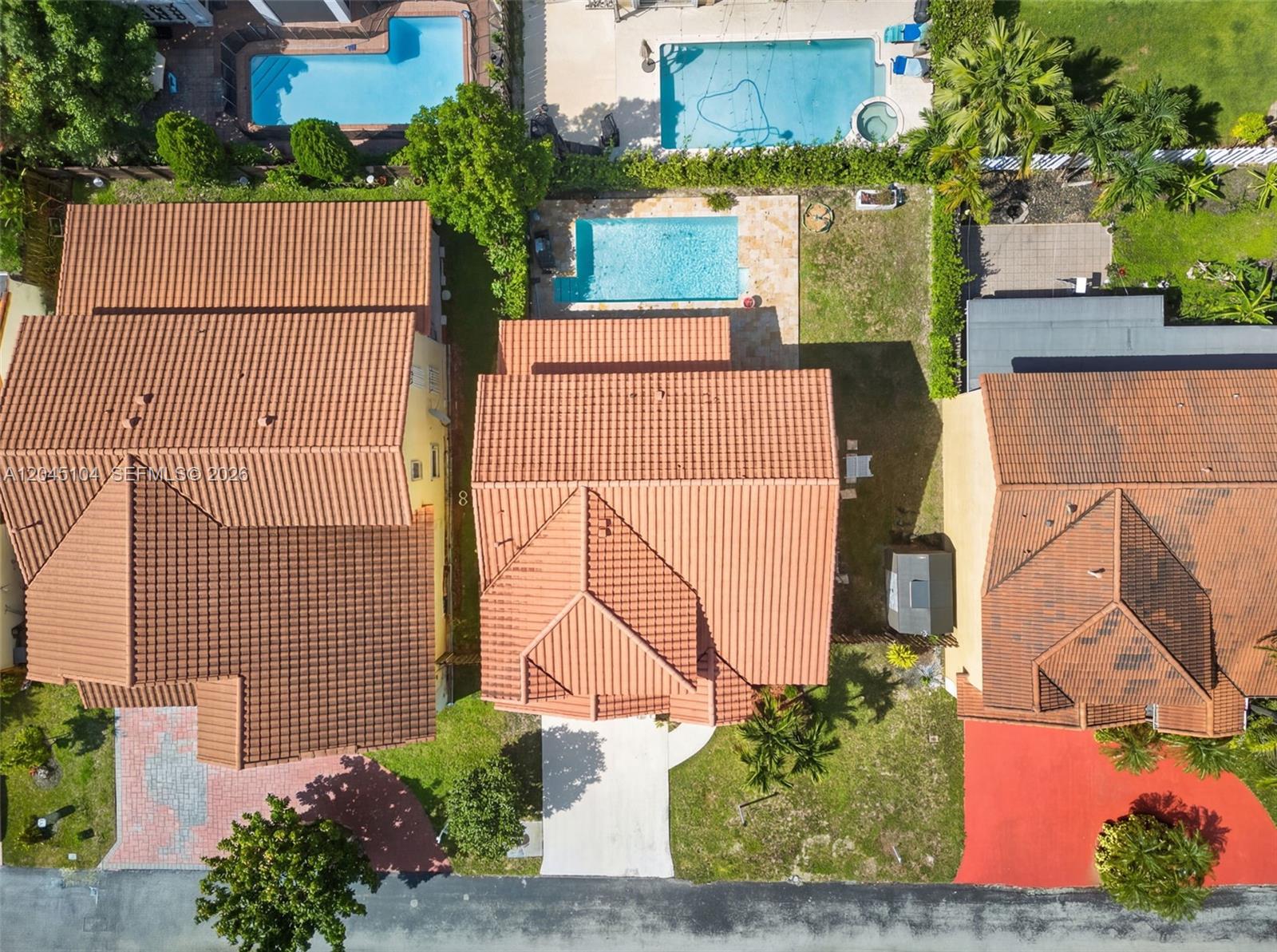An aerial view shows three suburban houses with tiled roofs, private pools, and driveways — 15602 SW 109th Ter, Miami FL 33196, MIAMI, FL