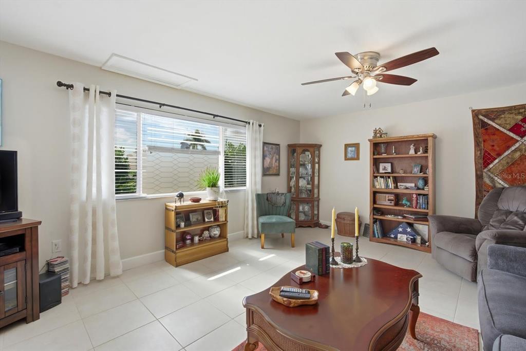 A living room with tile floors, a ceiling fan, a window, and wooden furniture — 2320 AQUABLUFF PLACE UNIT V274, SARASOTA, FL
