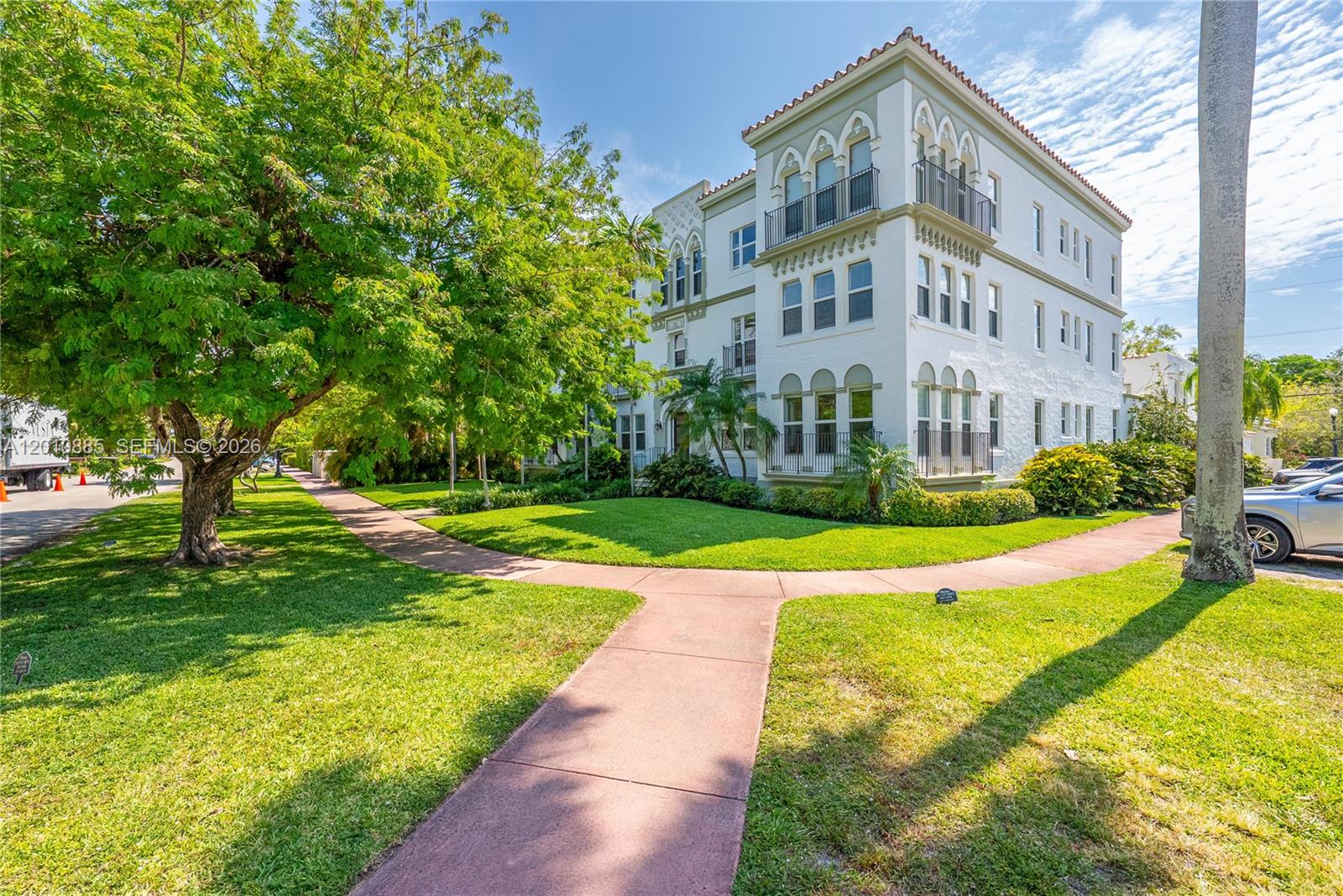 A three-story white stucco apartment building with arched windows and balconies sits on a lawn — 4501 Prairie Ave # 1, Miami Beach FL 33140, MIAMI BEACH, FL