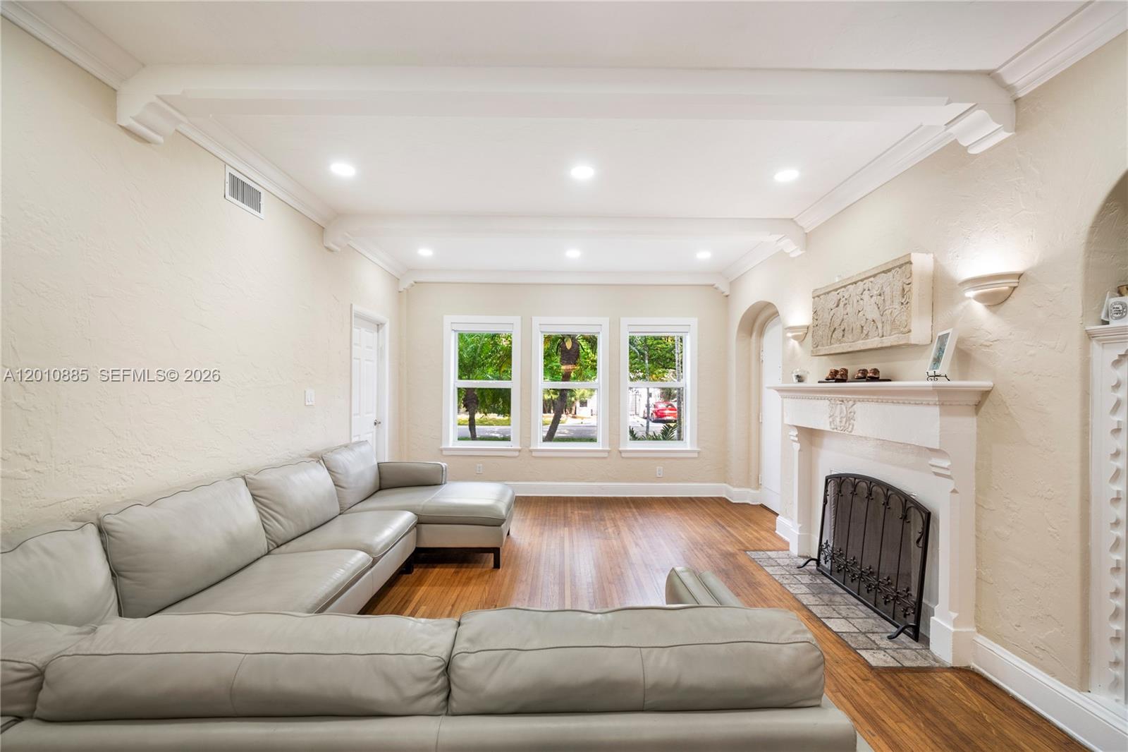 A living room features a light-colored sectional sofa, hardwood floors, and a fireplace — 4501 Prairie Ave # 1, Miami Beach FL 33140, MIAMI BEACH, FL
