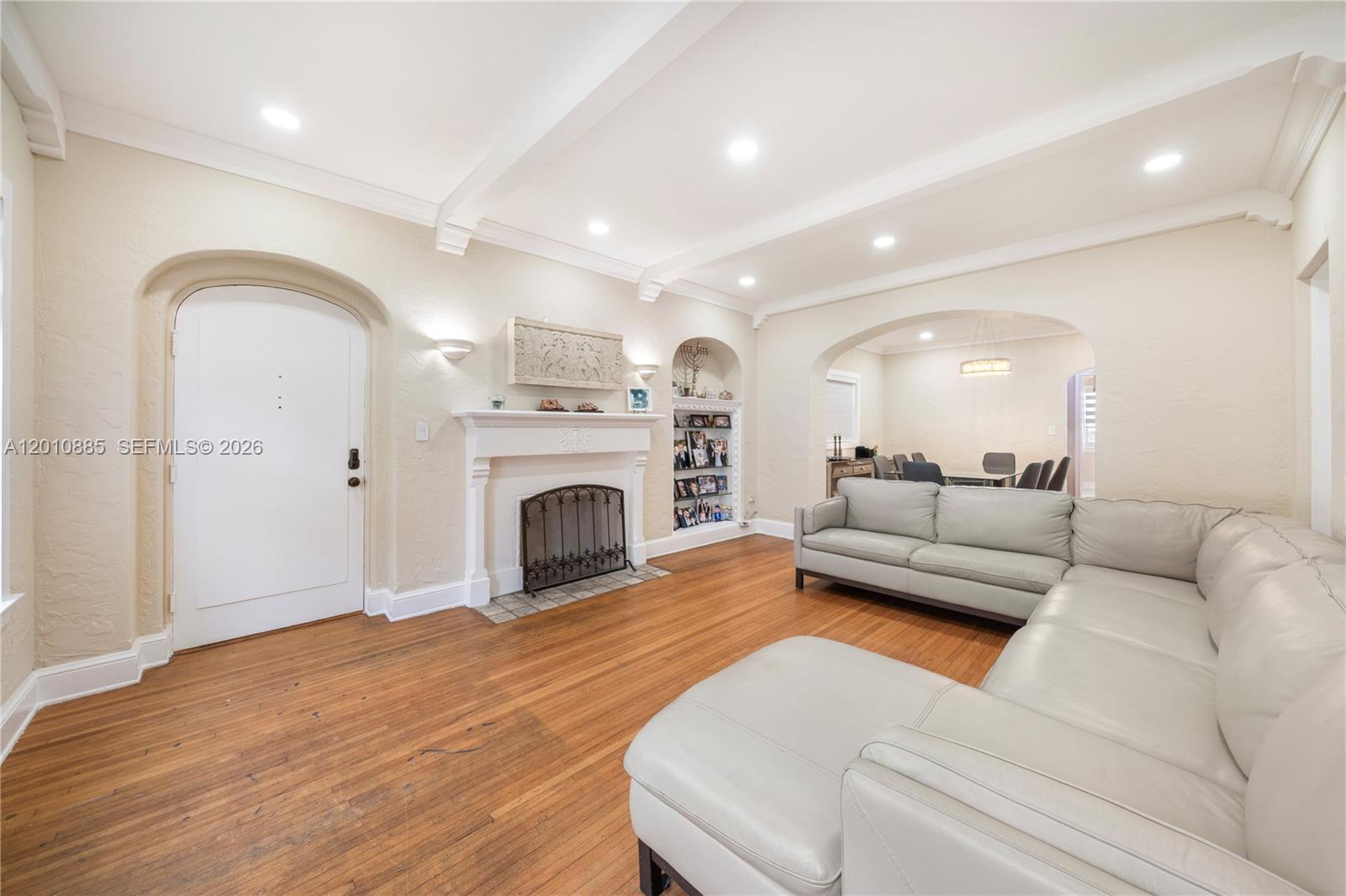 A living room features a fireplace, hardwood floors, a sectional sofa, and an arched doorway — 4501 Prairie Ave # 1, Miami Beach FL 33140, MIAMI BEACH, FL