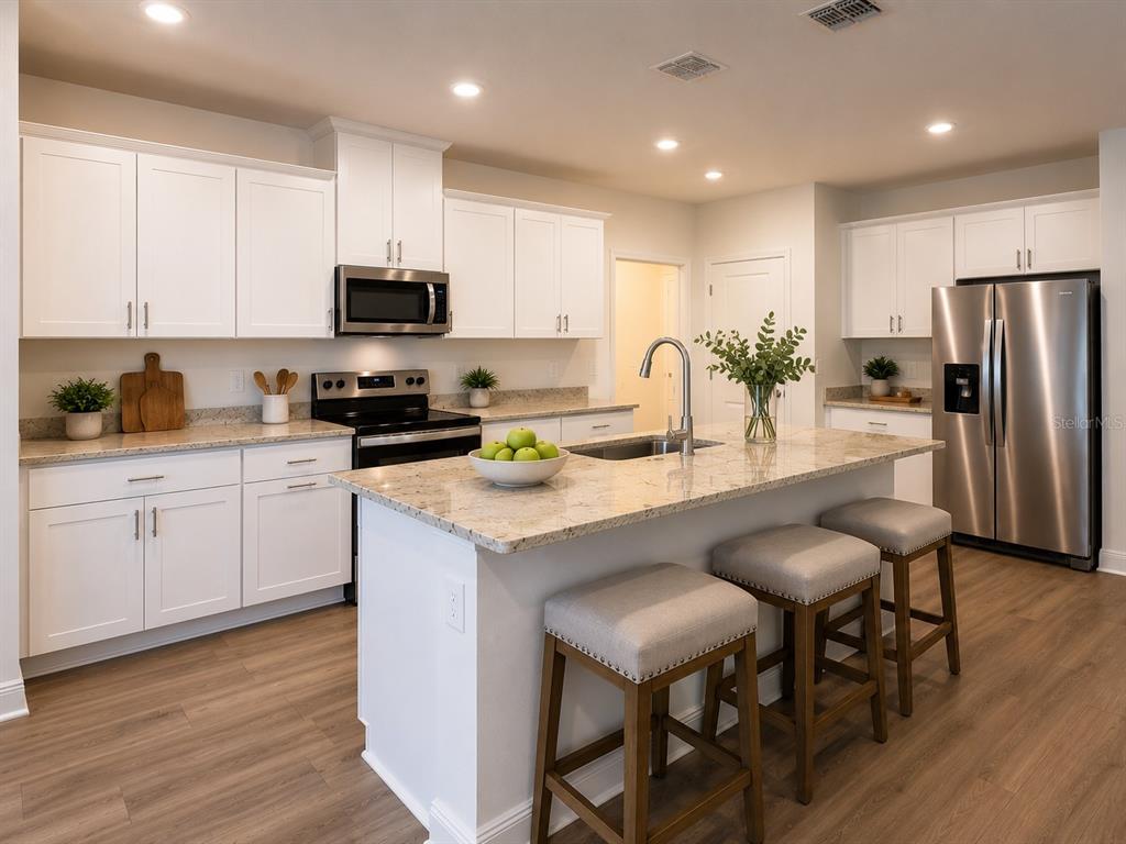 A modern kitchen features white cabinets, granite countertops, a center island, and stainless steel appliances — 1789 ARCHER DRIVE, MINNEOLA, FL