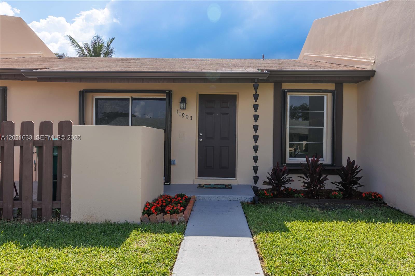 The exterior of a single-story home features a brown front door, a walkway, and landscaping — 11903 SW 110th St Cir E # 11903, Miami FL 33186, MIAMI, FL