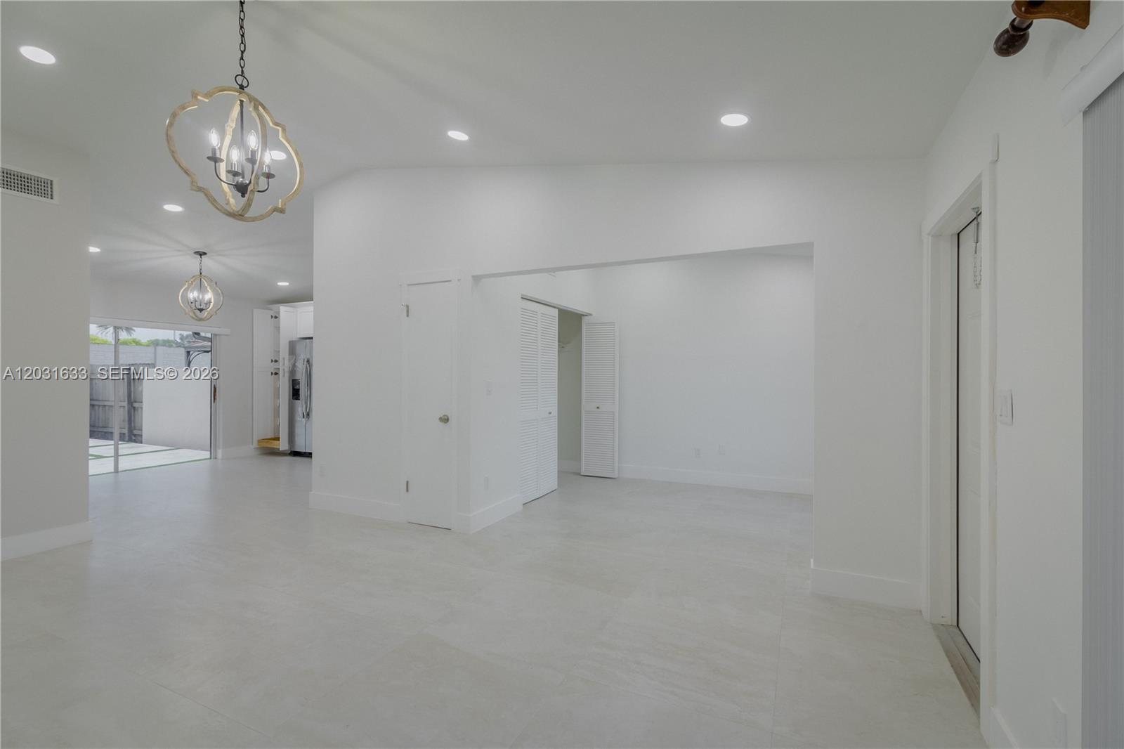 A bright, open-concept living area features white walls, light tile flooring, and two decorative chandeliers — 11903 SW 110th St Cir E # 11903, Miami FL 33186, MIAMI, FL