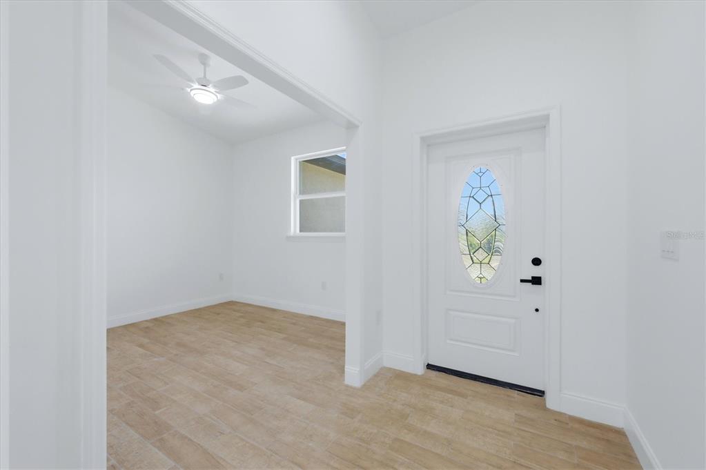 An entryway with light wood-look tile flooring leads into an adjacent room with a ceiling fan — 6 BANK COURT, PLACIDA, FL