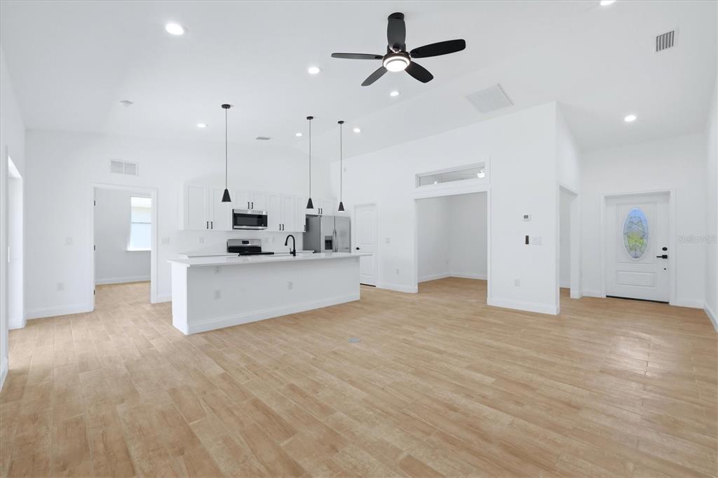A bright, open-concept kitchen and living area features white cabinetry, a kitchen island, and light-colored flooring — 6 BANK COURT, PLACIDA, FL