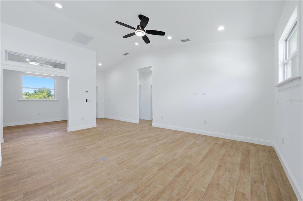 A bright, empty living room features white walls, light wood-look tile flooring, and a ceiling fan — 6 BANK COURT, PLACIDA, FL