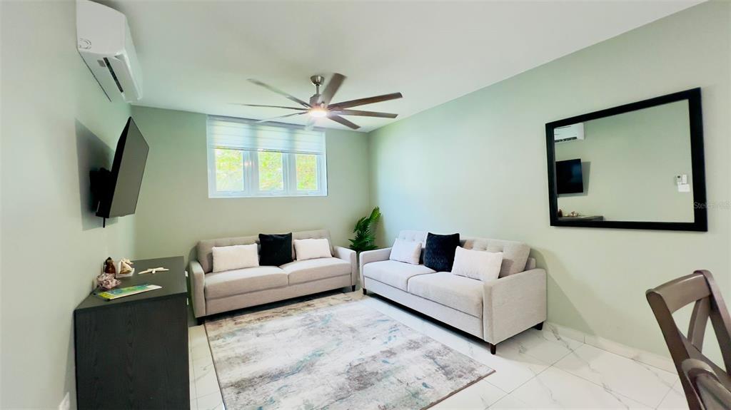 A living room with two light-colored sofas, a ceiling fan, and a large wall mirror — Km 4.7 CARR 413 INT UNIT 102, RINCON, PR