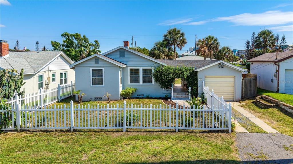 A light blue single-story house features a white picket fence and an attached garage — 129 ROSALYN AVENUE, DAYTONA BEACH, FL