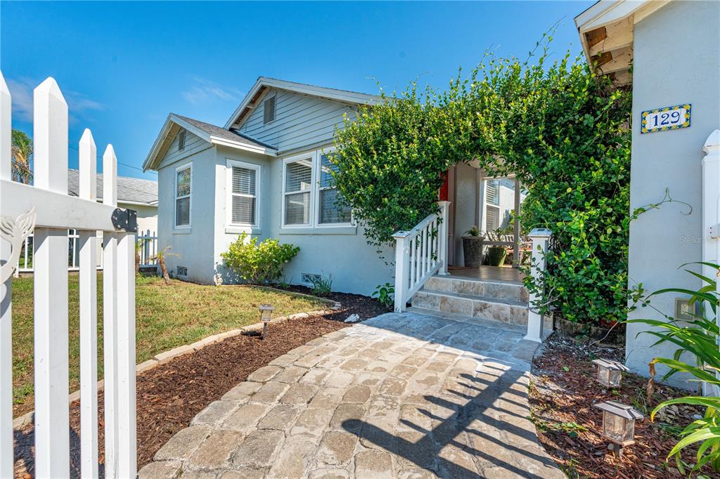 A stone walkway leads to the front porch of a light-colored house with white trim — 129 ROSALYN AVENUE, DAYTONA BEACH, FL