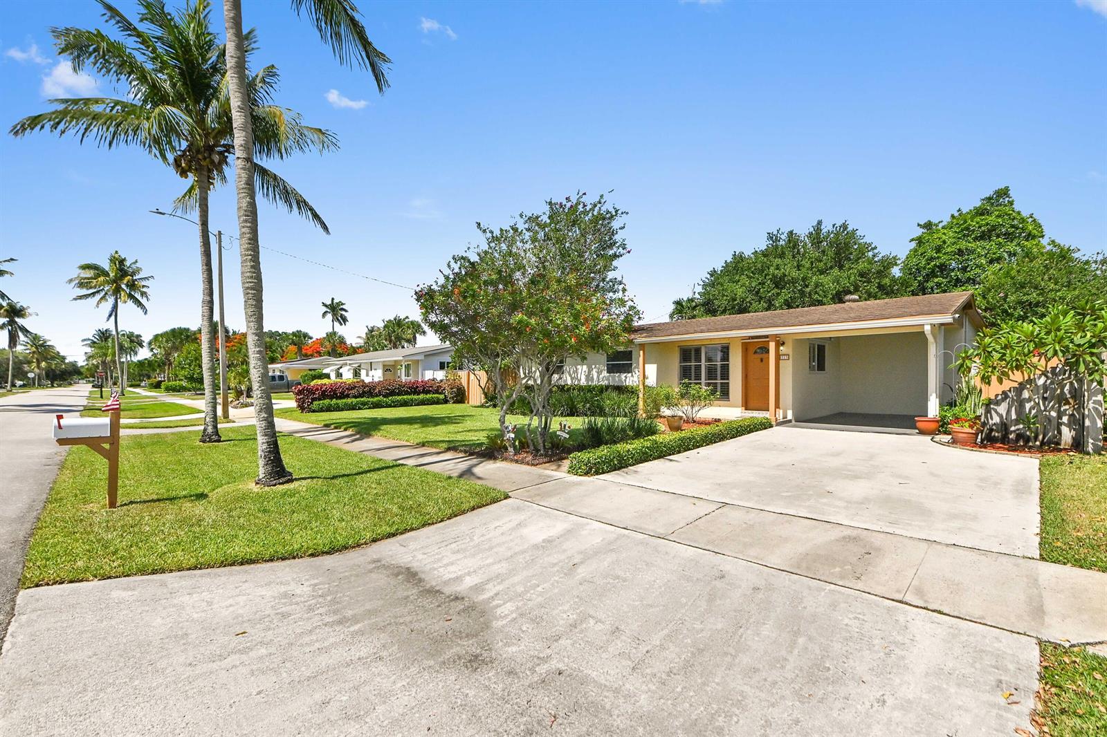 A single-story house with a concrete driveway, carport, and palm trees in the front yard — 313 Poe Drive, Palm Springs FL 33461, PALM SPRINGS, FL