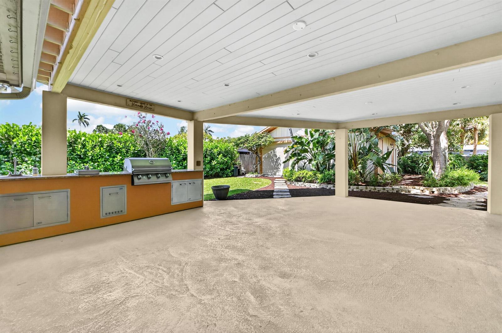A covered outdoor patio features a built-in kitchen with a grill and stainless steel cabinets — 313 Poe Drive, Palm Springs FL 33461, PALM SPRINGS, FL