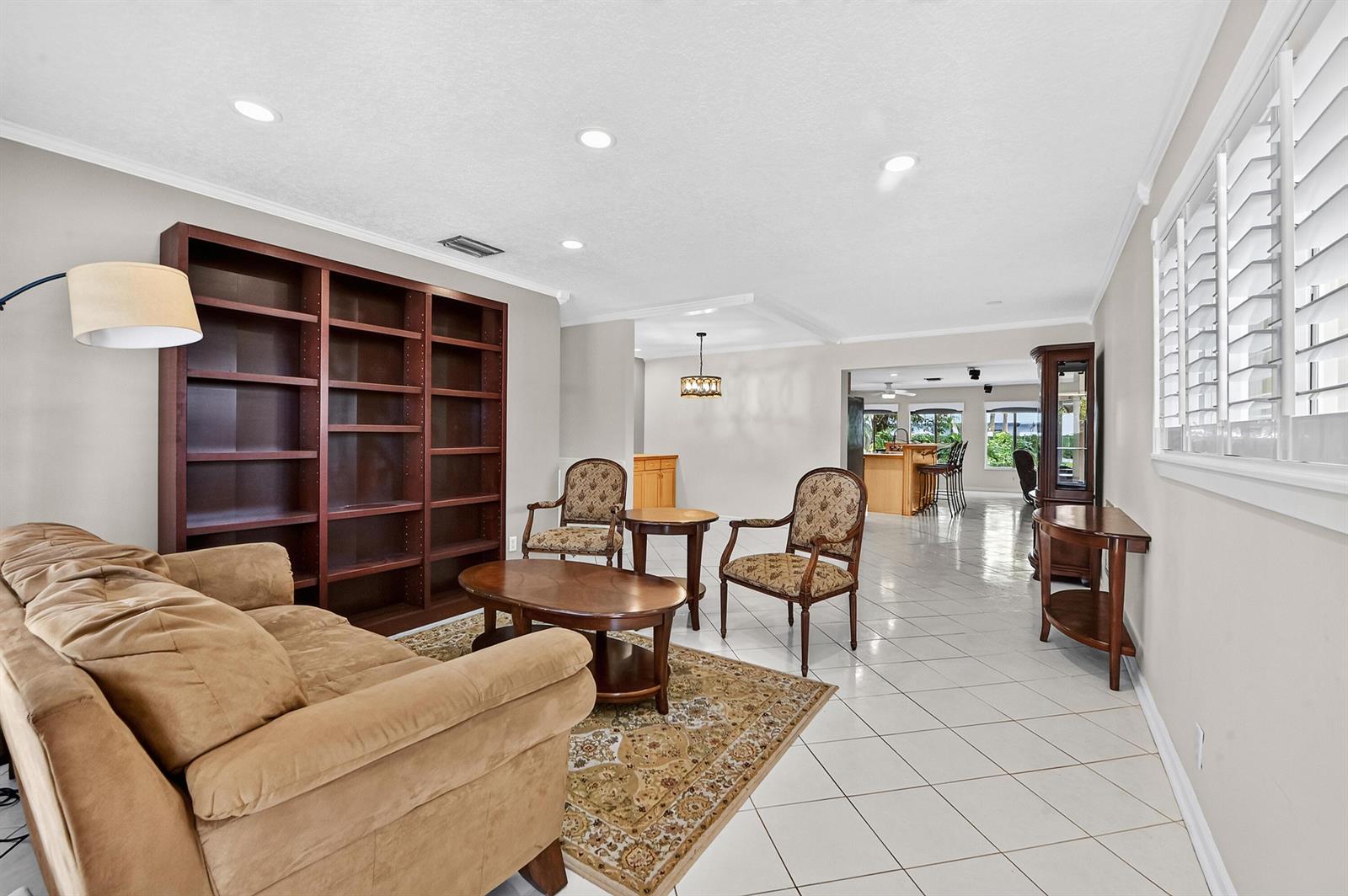 A living room features a tan sofa, two patterned chairs, a bookshelf, and tile flooring — 313 Poe Drive, Palm Springs FL 33461, PALM SPRINGS, FL