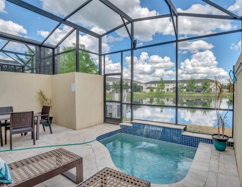 A screened-in patio features a small pool with a waterfall and views of a pond — 3115 TOCOA CIRCLE, KISSIMMEE, FL