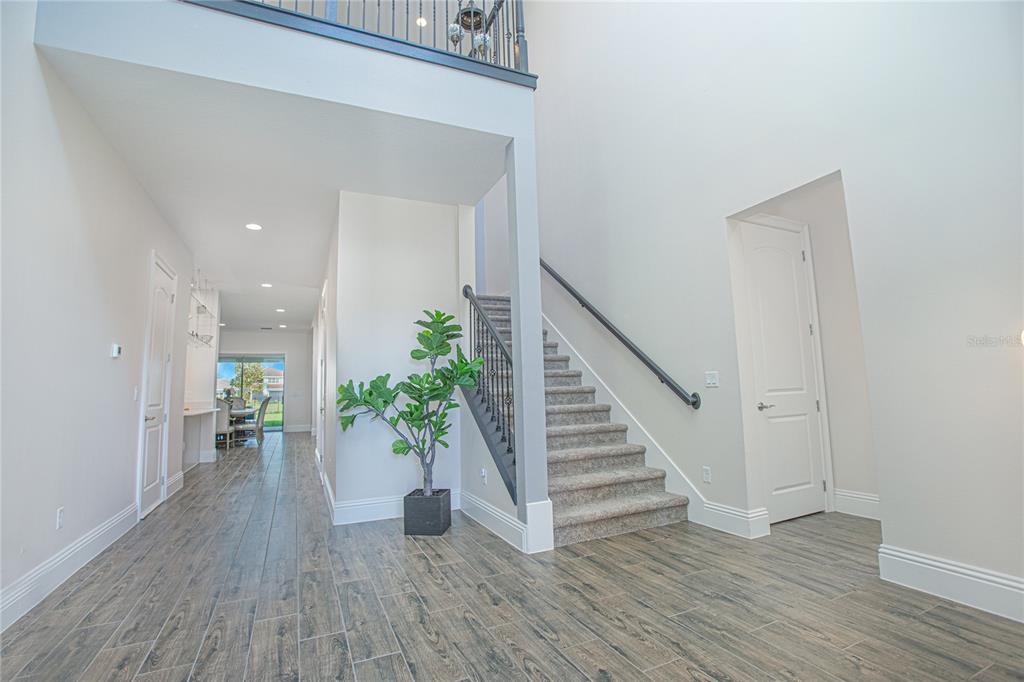 A foyer with wood-look tile flooring features a staircase and a view toward a dining area — 10846 MOBBERLEY CIRCLE, ORLANDO, FL