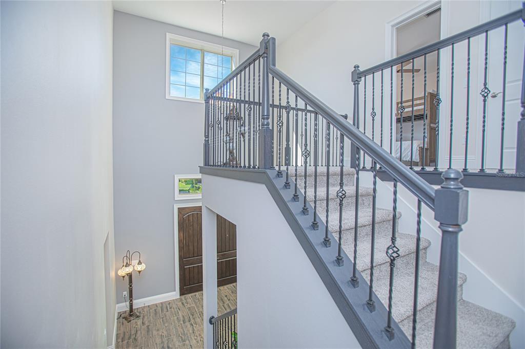 A staircase with gray railings and carpeted steps leads to an upper landing in a foyer — 10846 MOBBERLEY CIRCLE, ORLANDO, FL
