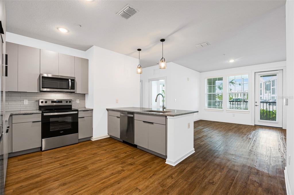 A modern kitchen with grey cabinets, stainless steel appliances, and an island with a sink — 1700 RANCH ROAD UNIT B1-13112, NOKOMIS, FL
