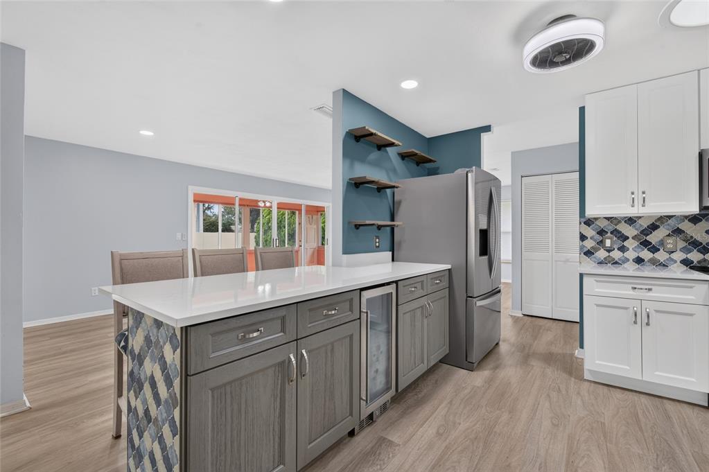 A kitchen features a gray island with a wine cooler, white cabinets, and blue accents — 113 DUSK MEADOW TRAIL, PORT ORANGE, FL