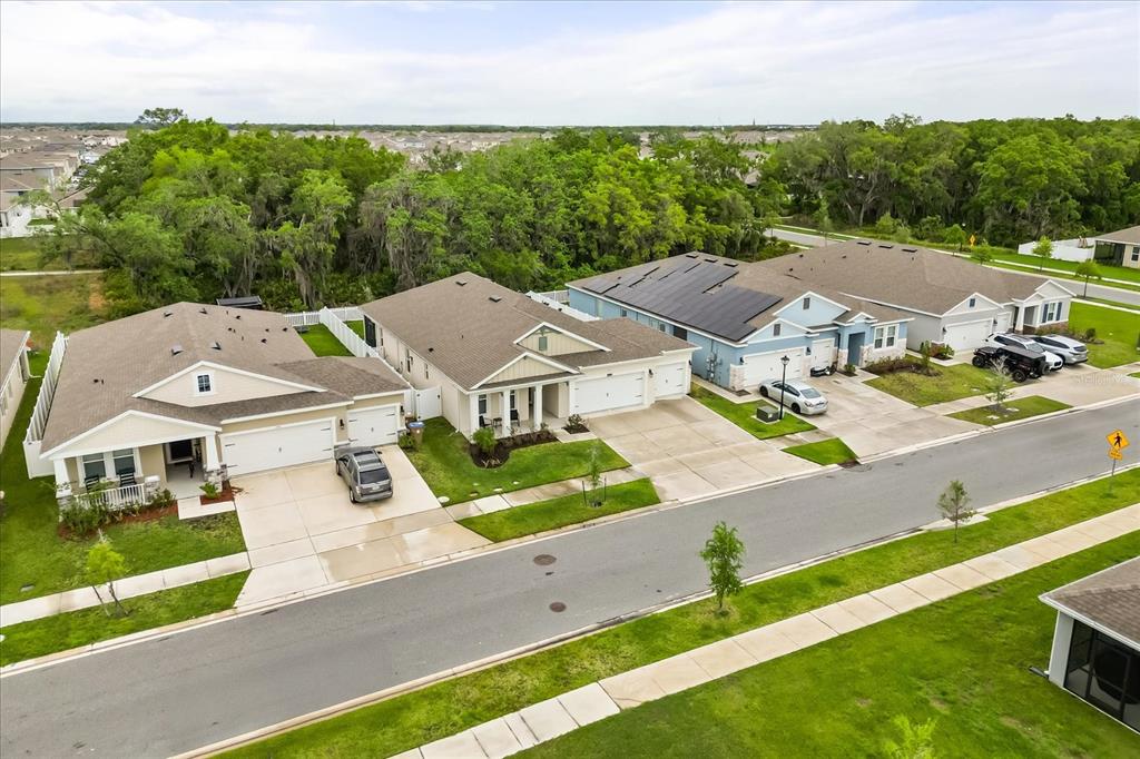 An aerial view shows three suburban houses with driveways and lawns bordering a wooded area — 1967 RANKIN ST, KISSIMMEE, FL