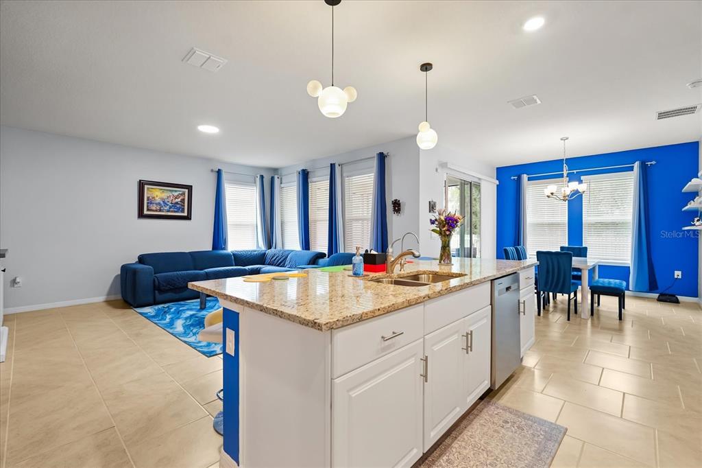 A kitchen island with granite countertops overlooks a living room and dining area — 1967 RANKIN ST, KISSIMMEE, FL