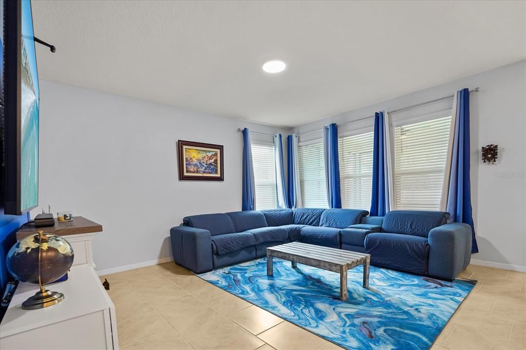 A living room features a blue sectional sofa, a patterned rug, and tile flooring — 1967 RANKIN ST, KISSIMMEE, FL