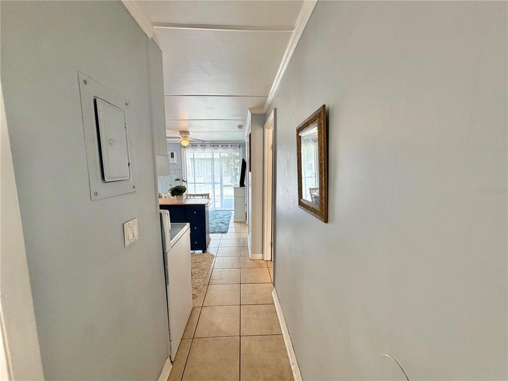 A hallway with light-colored tile floors leads toward a kitchen and a bright living area — 10301 US HIGHWAY 27 UNIT 192, CLERMONT, FL