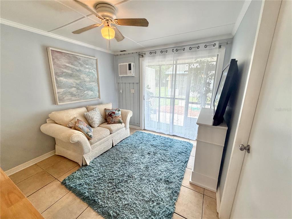 A living room features a beige sofa, a blue shag rug, and a sliding glass door — 10301 US HIGHWAY 27 UNIT 192, CLERMONT, FL