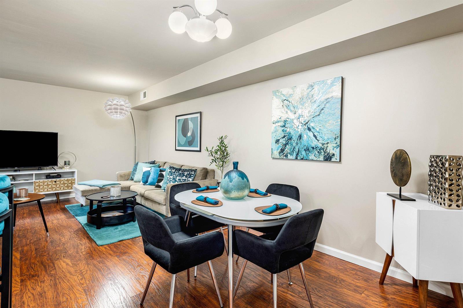 A living and dining area features hardwood floors, a neutral sofa, and modern blue accents — 14897 Bal Moral Lane # 105, Delray Beach FL 33446, DELRAY BEACH, FL