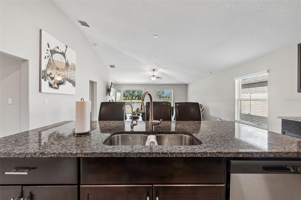 A kitchen island with a double sink and granite countertop overlooks an open living area — 1565 COLDING DRIVE, RUSKIN, FL