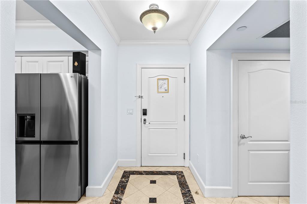 An entryway features a white door, a stainless steel refrigerator, and tiled flooring with borders — 7593 GATHERING DRIVE UNIT 307, KISSIMMEE, FL