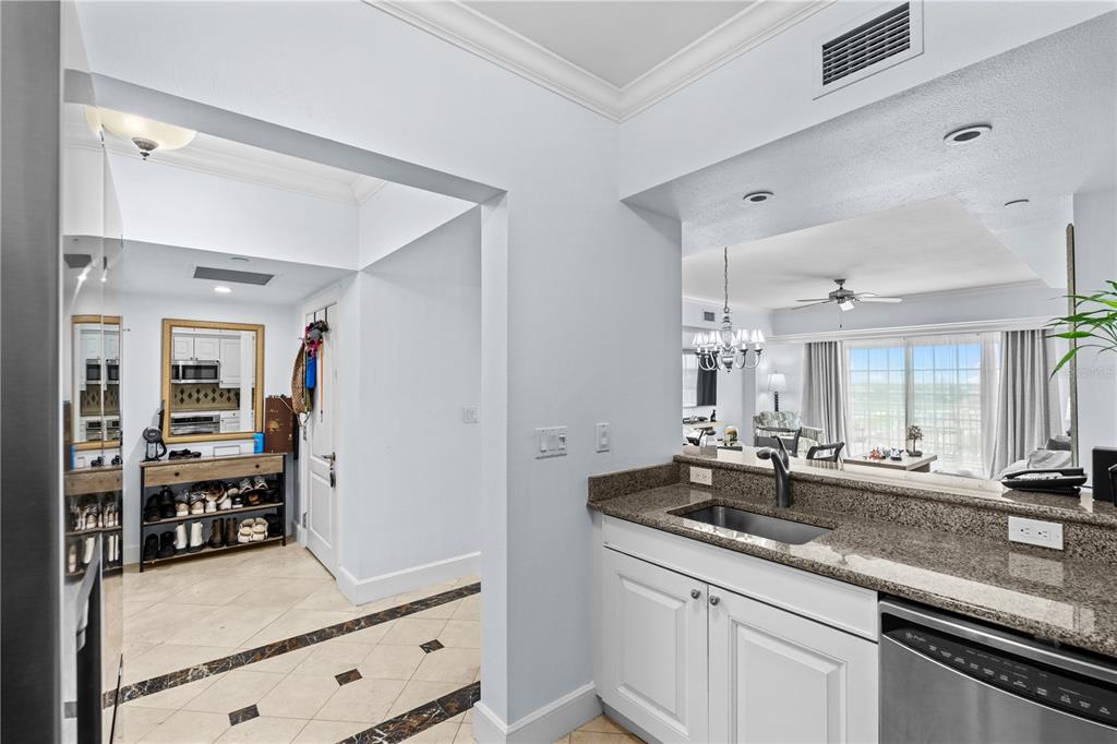 A kitchen with granite countertops and a sink overlooks a living area with tile floors — 7593 GATHERING DRIVE UNIT 307, KISSIMMEE, FL
