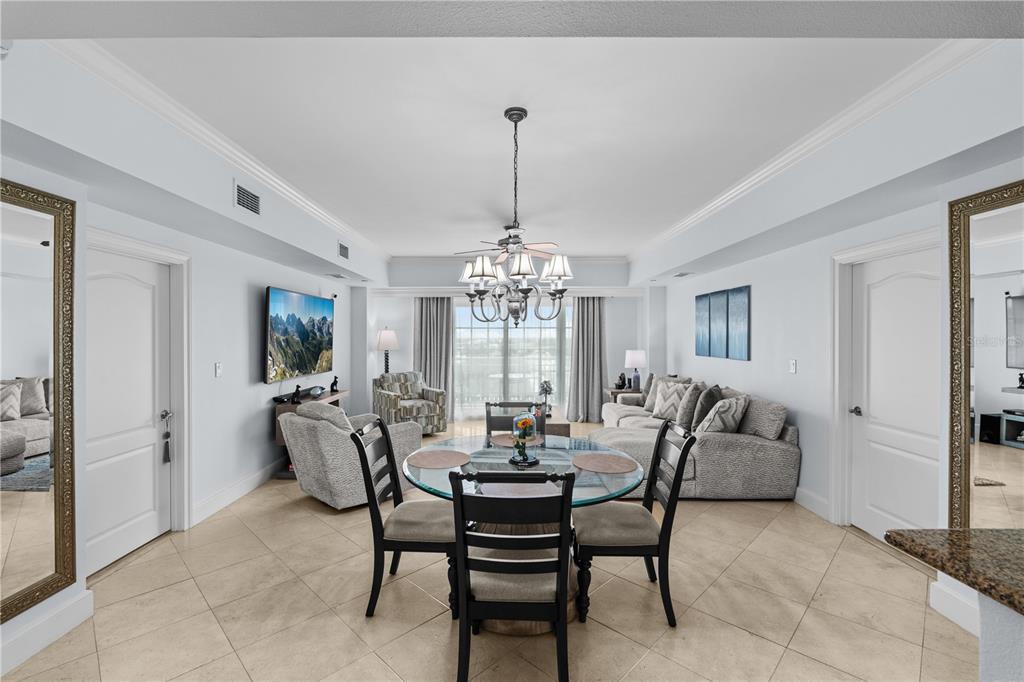 A dining area with a glass table sits in front of a living room with furniture — 7593 GATHERING DRIVE UNIT 307, KISSIMMEE, FL