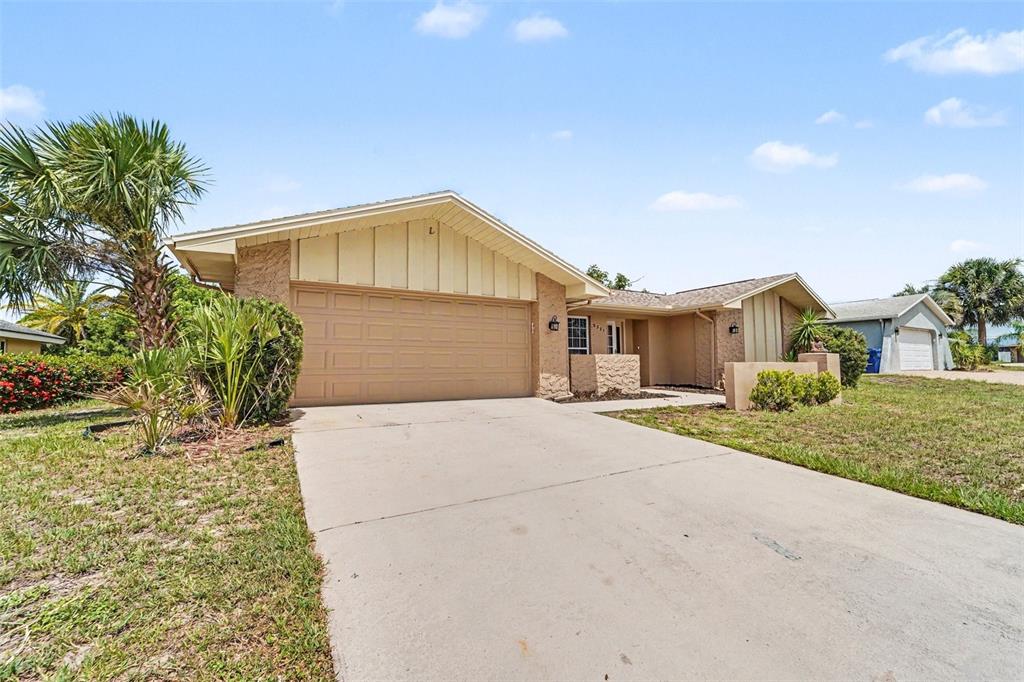 A single-story house with a tan exterior, a two-car garage, and a concrete driveway — 8321 BRIARLEAF COURT, PORT RICHEY, FL