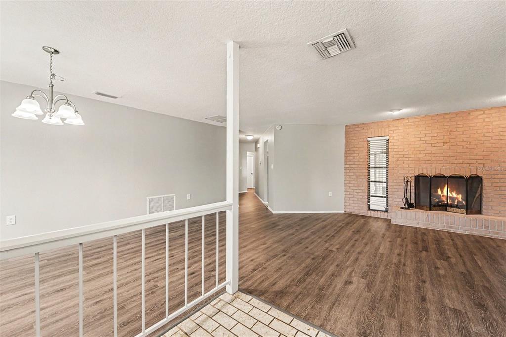 A living room features wood-look flooring, a brick fireplace, and a white metal railing — 8321 BRIARLEAF COURT, PORT RICHEY, FL