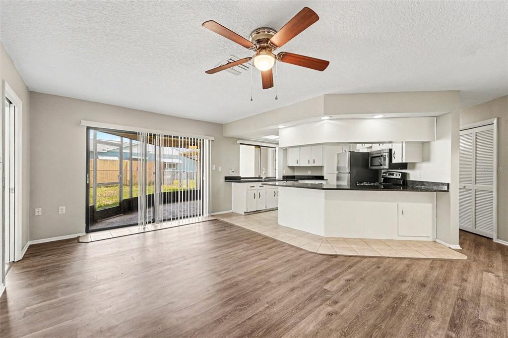 A living room with wood-look flooring opens to a kitchen with white cabinets and counters — 8321 BRIARLEAF COURT, PORT RICHEY, FL