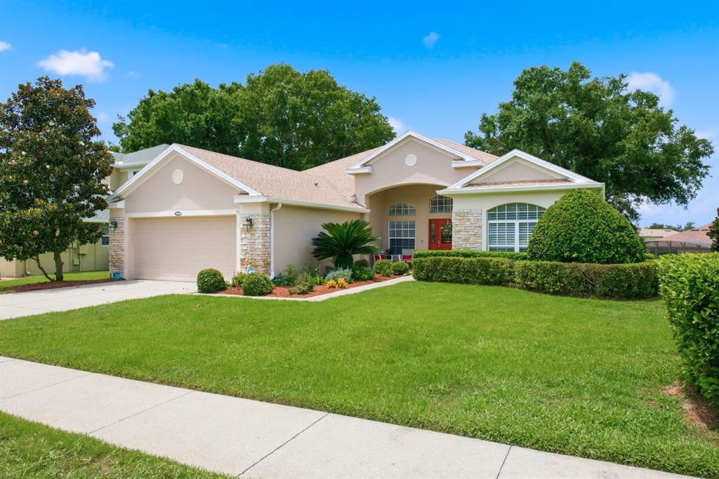 A single-story suburban house with a beige stucco exterior, stone accents, and a two-car garage — 3900 LIBERTY HILL DRIVE, CLERMONT, FL
