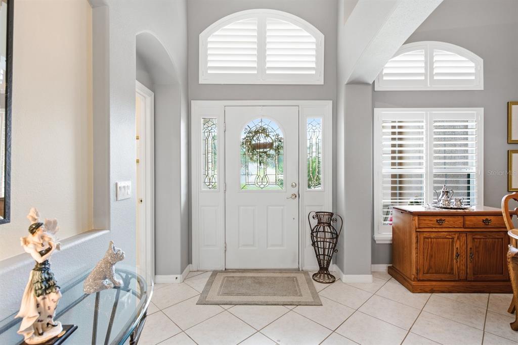 A bright entryway features a white front door with sidelights, arched windows, and tile flooring — 3900 LIBERTY HILL DRIVE, CLERMONT, FL