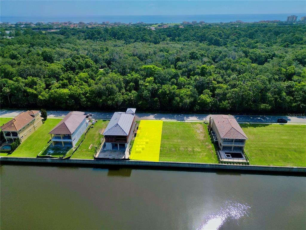 An aerial view shows a vacant waterfront lot highlighted in yellow between two existing houses — 244 HARBOR VILLAGE POINT N, PALM COAST, FL