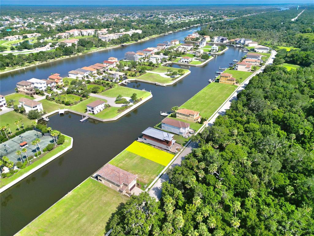 An aerial view shows waterfront homes with a highlighted vacant lot along a canal — 244 HARBOR VILLAGE POINT N, PALM COAST, FL