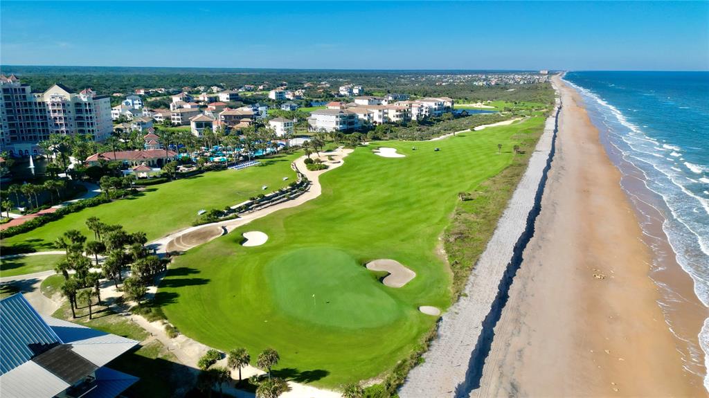 An aerial view shows a golf course green situated directly beside a sandy beach and ocean — 244 HARBOR VILLAGE POINT N, PALM COAST, FL