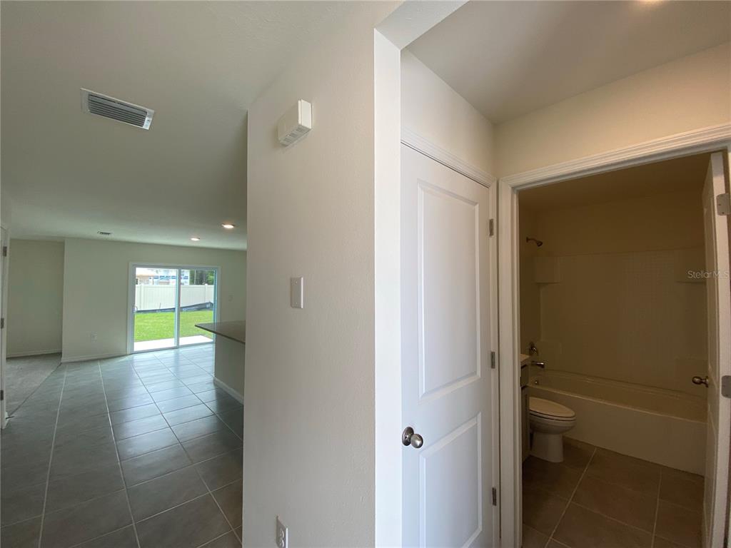 A view from a hallway looking into a tiled living area and a bathroom — 2113 NW 247 DRIVE, NEWBERRY, FL