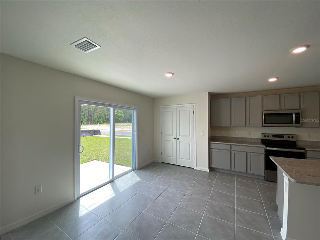 A kitchen and dining area with gray cabinets, tile flooring, and a sliding glass door — 2113 NW 247 DRIVE, NEWBERRY, FL